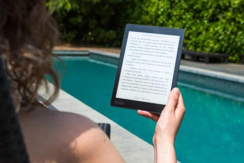 Woman reading kindle by the pool